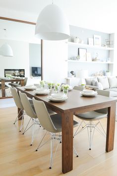 a dining room table with chairs and plates on it in front of the couches