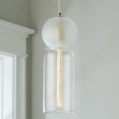 a light fixture hanging from the ceiling in a room with white walls and window sill