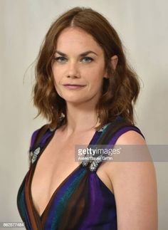 a woman in a purple dress posing for the camera with her hair pulled back and shoulder length