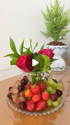 a glass bowl filled with fruit and flowers on top of a table next to two vases