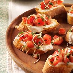 several pieces of bread with tomatoes and cheese on them sitting on a wooden platter