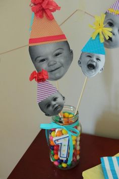 a jar filled with candies and pictures of babies in hats on top of a table