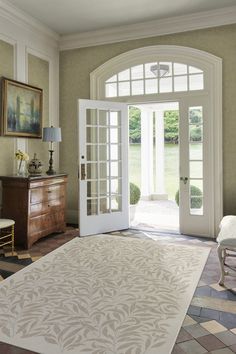 a living room with a large rug on the floor and french doors leading to an outside patio