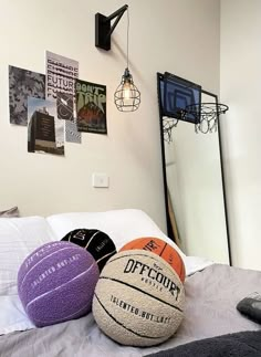 three basketballs sitting on top of a bed next to a mirror