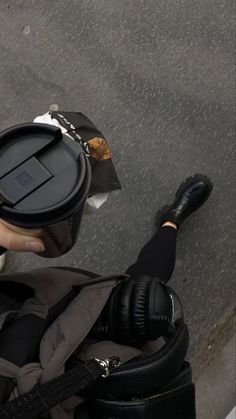 a person with headphones is holding a coffee cup in their hand while walking down the street