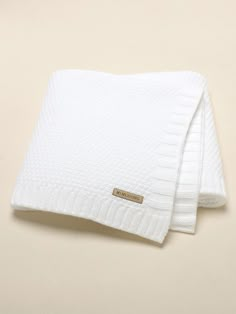 two white towels folded on top of each other in front of a beige background,