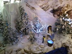 there is a fake snow scene with trees and lights on the mountain side, as well as a man sitting in a chair