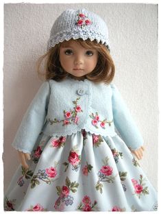 the doll is wearing a blue dress with pink flowers on it and a white hat