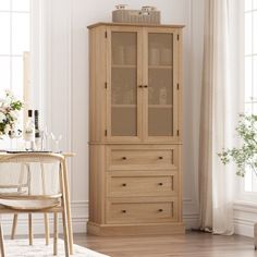 a tall wooden cabinet sitting next to a chair in a room with white walls and windows