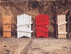 four wooden doors are lined up against a stone wall, one is painted red and the other is white