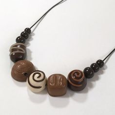 a necklace made out of chocolates and nuts on a white surface with black string