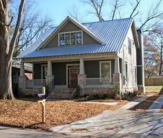 a small house with a metal roof and front porch is shown in the fall leaves