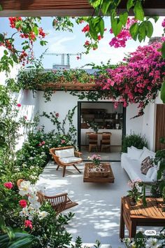 an outdoor living area with wicker furniture and pink flowers on the wall, surrounded by greenery