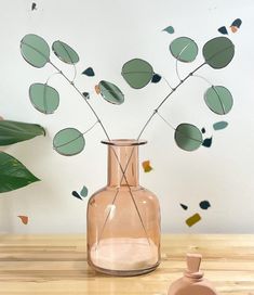 a vase filled with green leaves on top of a wooden table