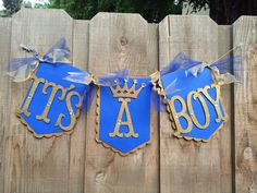 blue and gold banner hanging from wooden fence with crown on it's head, let's a boy