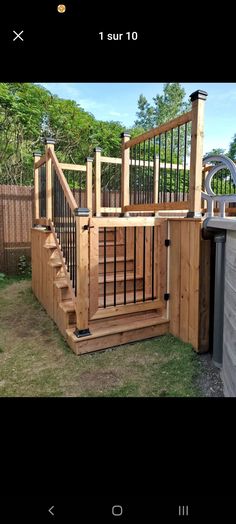 a wooden deck with stairs and railings next to a fenced in backyard area