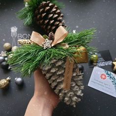 a hand holding a pine cone with christmas decorations around it