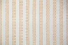 an orange and white striped wallpaper with small circles on the bottom half of it