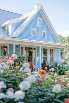 a blue house with flowers in the front yard