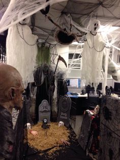 halloween decorations are on display in a room with white walls and black flooring, including fake tombstones