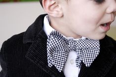 a young boy wearing a black and white checkered bow tie with his mouth open