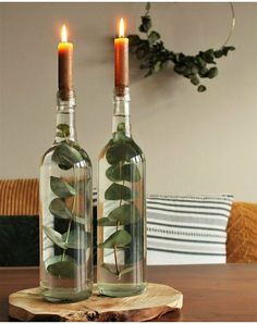 two wine bottles with plants in them sitting on a wooden table next to each other