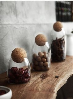 three glass jars filled with nuts and dried cranberries on a wooden table top