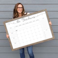 a woman holding up a large framed calendar