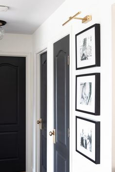 black and white photos hang on the wall next to two doors with gold handles in a hallway