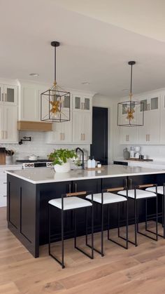 a large kitchen with white cabinets and black island