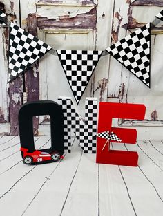 the letter e is decorated with black and white checkered pennants next to a red toy car