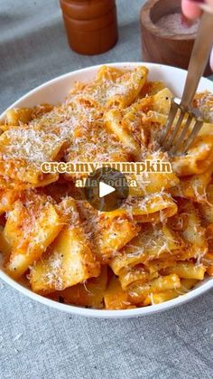 a white bowl filled with pasta covered in parmesan cheese