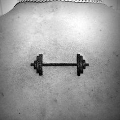 the back of a woman's body with a barbell tattoo on her chest