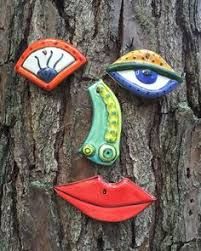 three ceramic eyes are attached to the bark of a tree, each with an eye on it