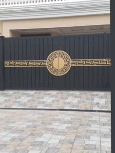 a black and gold gate in front of a house with a brick walkway next to it