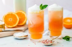 two glasses filled with orange juice and garnished with mint