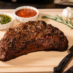 a steak on a cutting board with some condiments