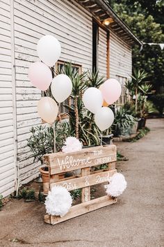 a welcome sign with balloons and pom poms