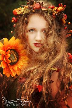 a woman with long curly hair wearing a wreath and holding a sunflower in her hand