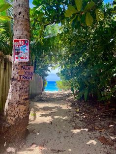 a sign is posted on the side of a tree in front of a fence and beach