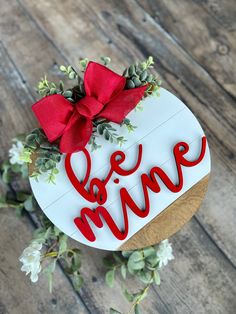 a cake with the word love on it and a red bow is sitting on a wooden table