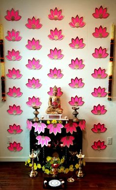 there is a small shrine with pink flowers on the wall and candles in front of it