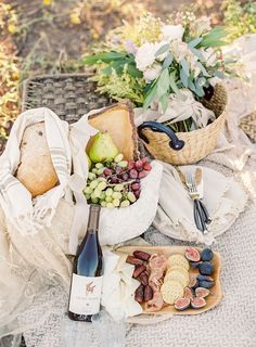 a table topped with lots of different types of food and wine next to baskets filled with fruit