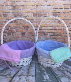 two baskets sitting next to each other on top of a wooden floor near a brick wall