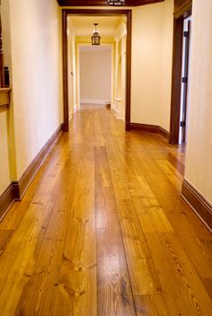 an empty hallway with hard wood floors and white walls