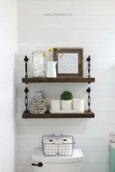 two shelves above a toilet in a bathroom with white walls and wood trimmings