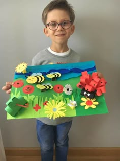 a young boy holding up a paper cut out of flowers