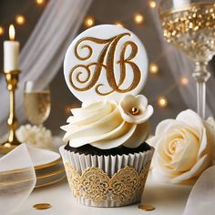 a cupcake with white frosting and gold trim sits on a table next to champagne glasses