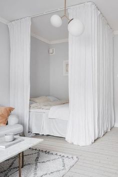 a bedroom with white walls and curtains on the windowsills is decorated in neutral colors