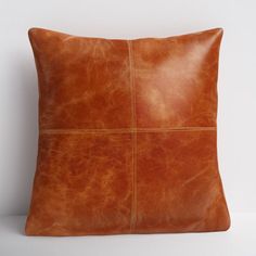 a brown leather pillow sitting on top of a white wall